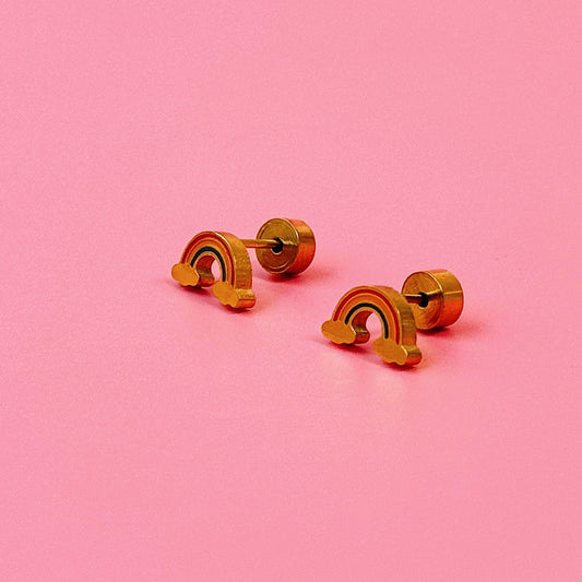 Gold rainbow-shaped earrings on a pink background