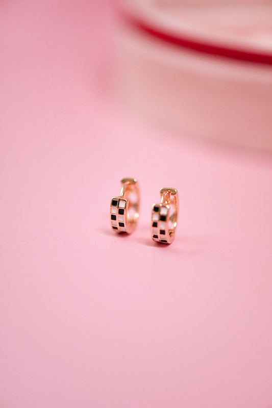 Rose gold hoop earrings on a pink background