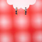 Gold hoop earrings with blue stones on a red and white background