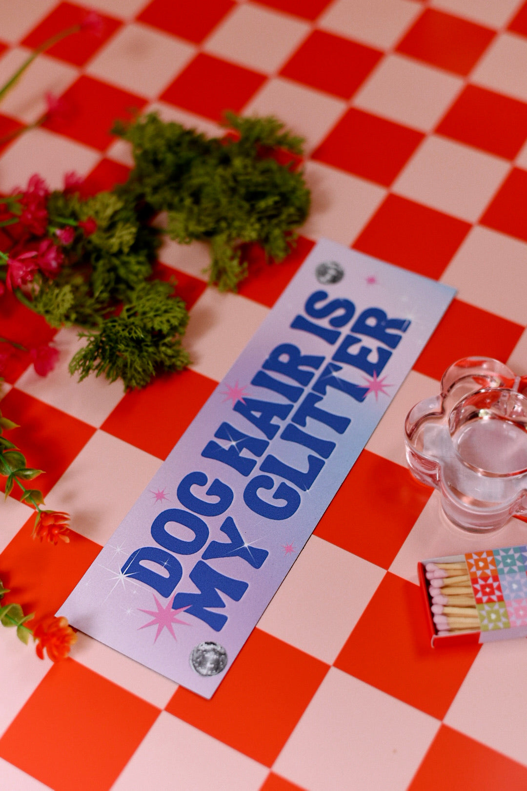 Sign with 'Dog hair is my glitter' on a red and white checkered tablecloth.