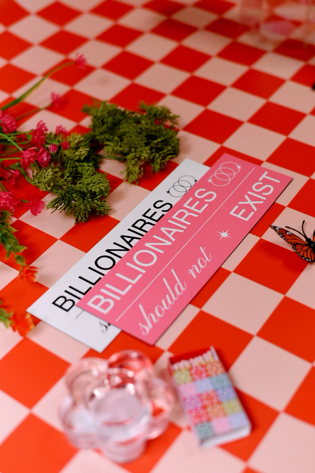 Two pink signs with text on a red and white checkered tablecloth.
