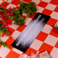 Decorative sign with text on a red and white checkered tablecloth with flowers and a butterfly.