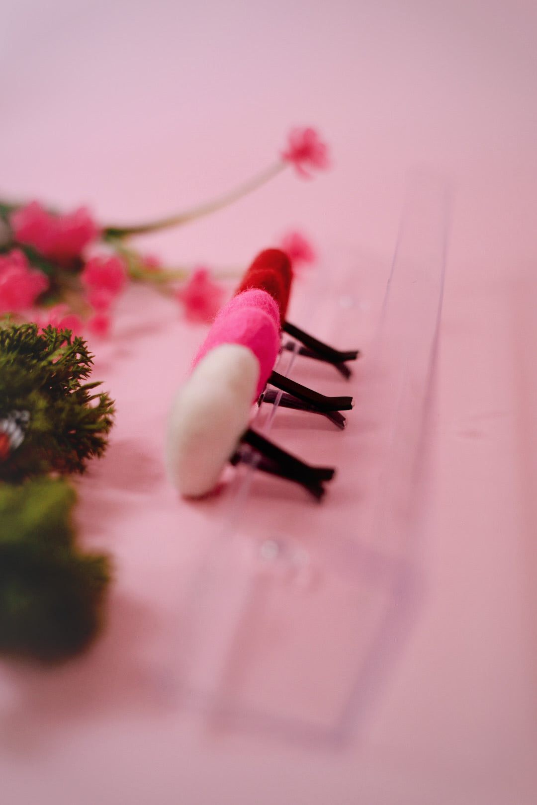 Pink red and white felt heart car vent clips on pink background with greenery in the background