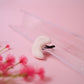 White car vent clip on a pink surface with blurred pink flowers in the foreground
