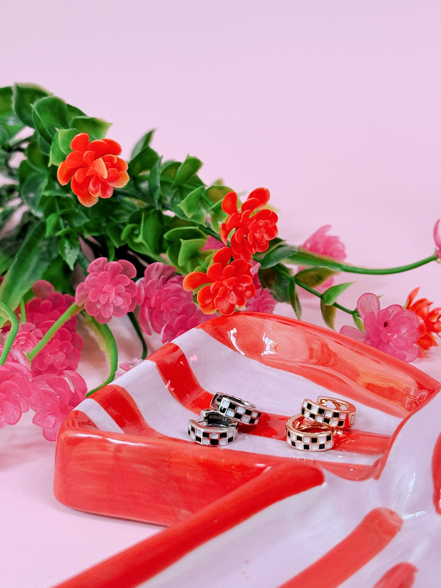 Set of rings on a red and white dish with flowers in the background