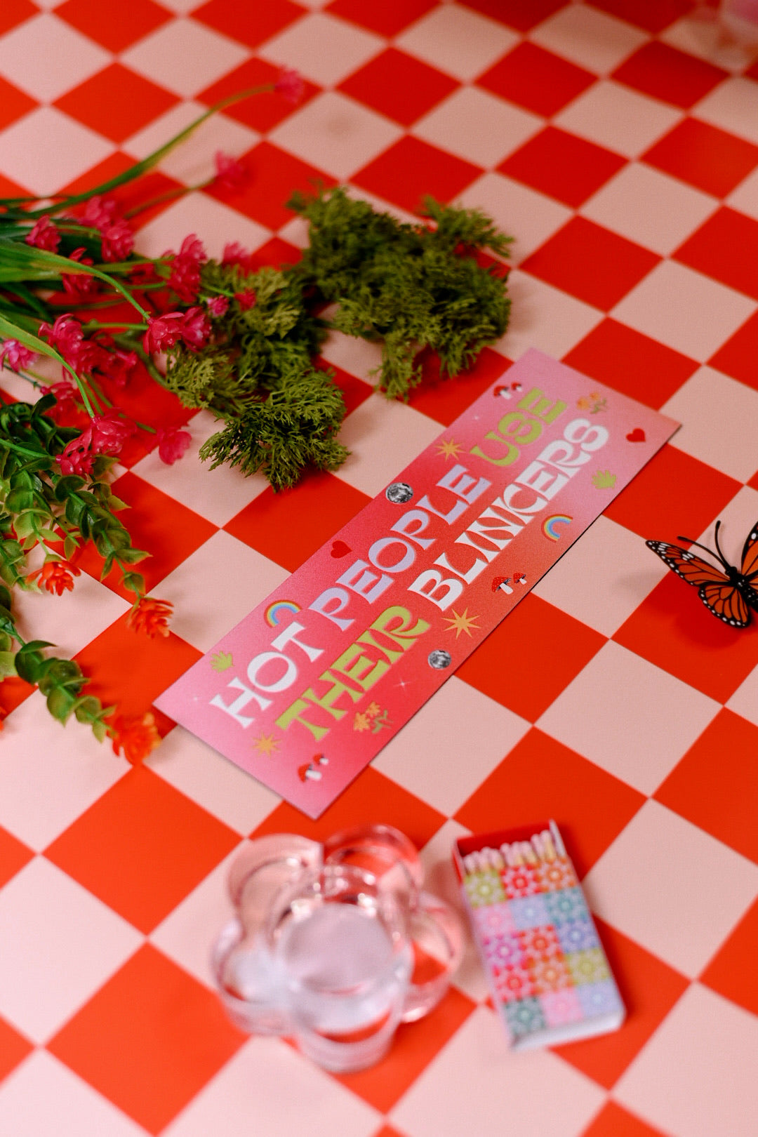 Car bumper magnet on a red and white checkered tablecloth with flowers and a butterfly.
