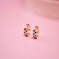 Rose gold hoop earrings on a pink background