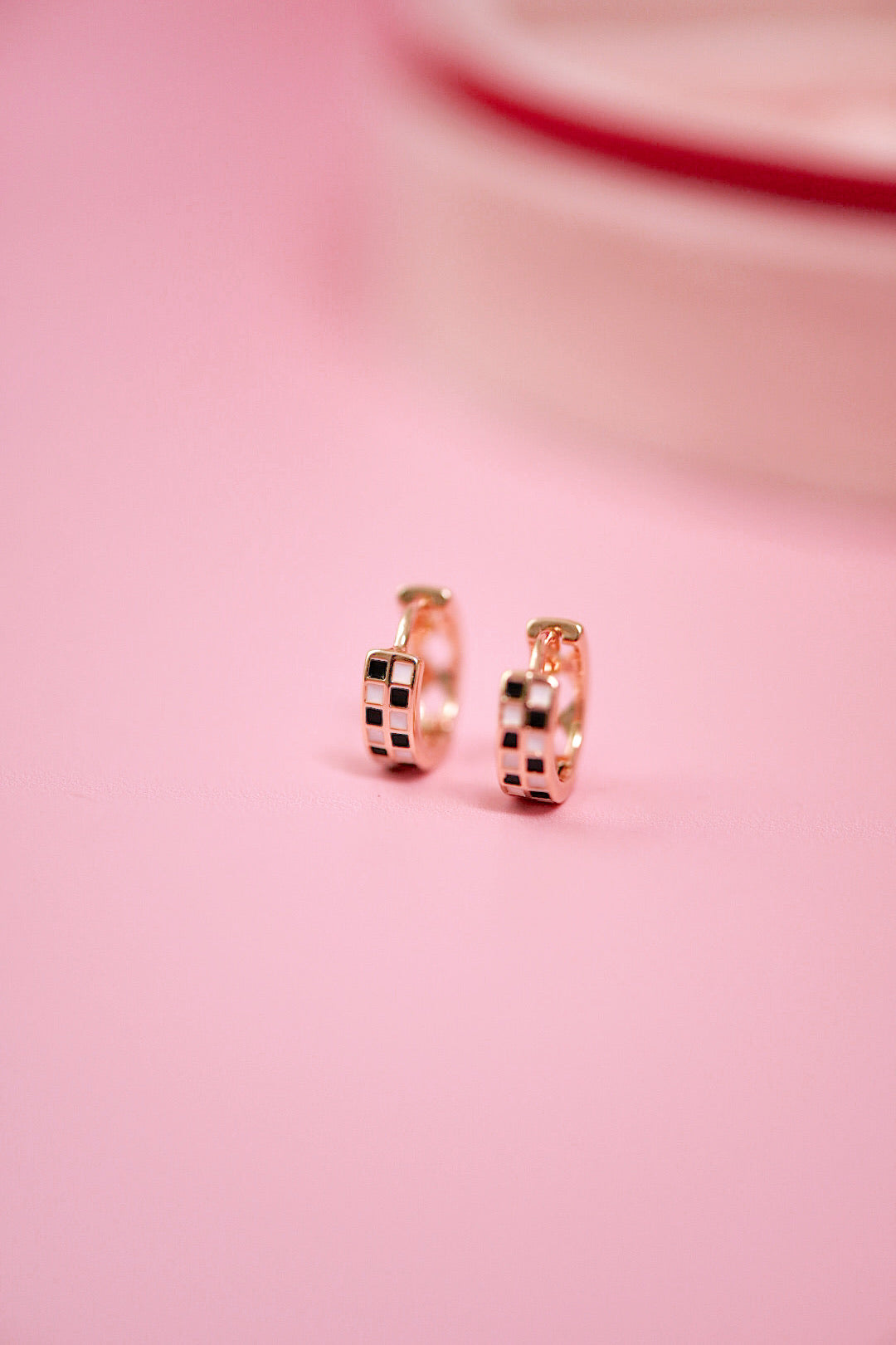 Rose gold hoop earrings on a pink background