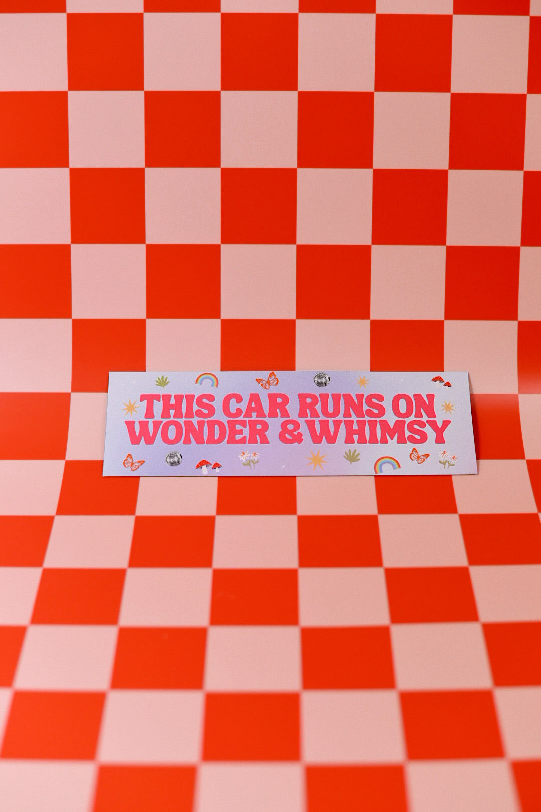 Card with 'This car runs on wonder & whimsy' text on a red and pink checkered background