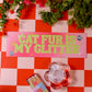 Decorative sign with 'Cat Fur is My Glitter' on a checkered background with flowers and matches.
