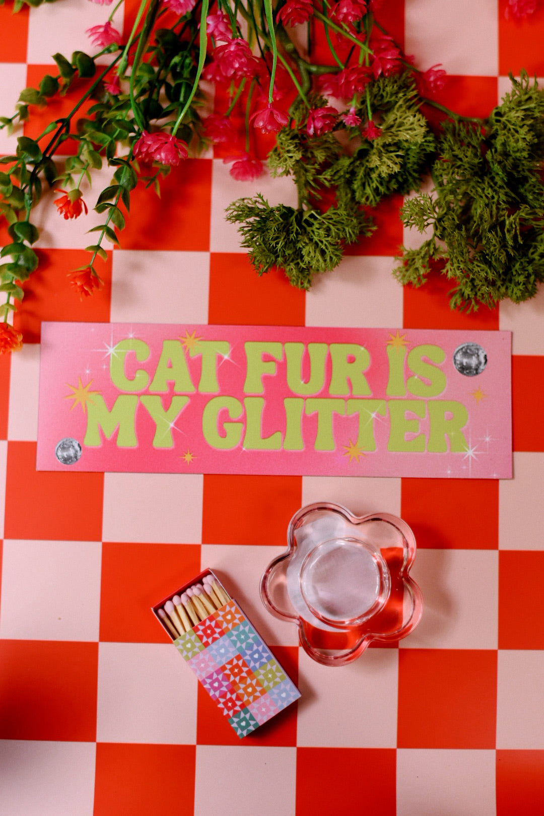 Decorative sign with 'Cat Fur is My Glitter' on a checkered background with flowers and matches.