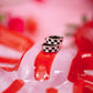 Close-up of a red and white striped object with checkered pattern on a pink background