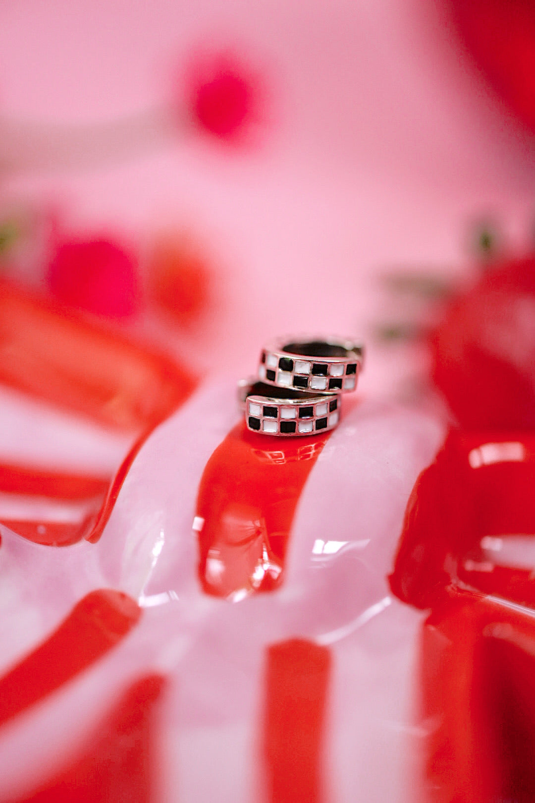 Close-up of a red and white striped object with checkered pattern on a pink background